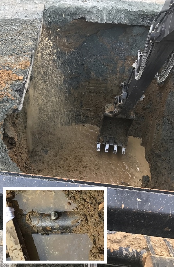 Picture of a hole dug in the ground exposing a water pipe that is spraying water